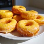 A stack of Delightful Baked Lemon Donuts with a glossy, zesty lemon glaze.