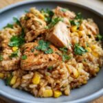 Close-up of a bowl filled with flavorful Mexican chicken and rice, featuring tender chicken pieces, corn, and fresh cilantro.