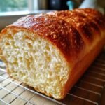 Close-up of a freshly baked loaf of Grandmas Perfect Homemade Bread, showing its golden crust and soft, airy crumb.
