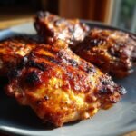 Close-up of perfectly grilled chicken thighs with a crispy, seasoned skin, showcasing the delicious texture.