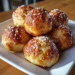 A pile of golden-brown, Irresistible Buttery Soft Pretzel Bites sprinkled with coarse salt.