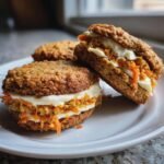 Two irresistible carrot cake cookies sandwiched with cream cheese frosting and shredded carrots.