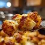 A fork lifts a piece of Irresistible Cheesy Ranch Oven Roasted Potatoes, showing melted cheese and crispy edges.