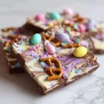 Close-up of Irresistible Easter Chocolate Bark, swirled with white and purple chocolate, topped with pastel candy eggs and sprinkles.