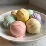 A plate of colorful Easter Egg Oreo Cookie Balls, drizzled with white chocolate.