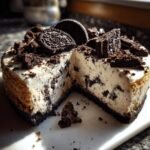A slice of irresistible Oreo cheesecake, topped with Oreo cookies and crumbs.