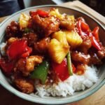 A close-up of an Irresistible Pineapple Chicken Stir Fry Recipe served over white rice in a bowl, featuring tender chicken, pineapple chunks, and bell peppers.