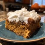 A delicious slice of Irresistible Pumpkin Poke Cake, topped with whipped cream, ready for fall.