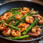 Close-up of Irresistible Sweet Chili Shrimp With Asparagus cooked in a skillet with a glossy sauce.