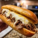 Close-up of an Ultimate Philly Cheese Steak Sandwich loaded with tender steak and plenty of melted cheese.