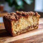 A delicious slice of Ultimate Sour Cream Coffee Cake with a crumb topping and cinnamon swirl.