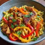 A close-up of Authentic Jerk Chicken Rasta Pasta, featuring tender jerk chicken pieces, creamy pasta, and colorful bell peppers.