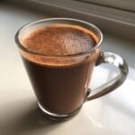 A steaming mug of rich Coconut Cream Hot Cocoa, topped with a layer of frothy foam.