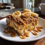 A decadent slice of Delicious Peanut Butter Banana Pudding topped with banana slices, peanut butter drizzle, and crumble.