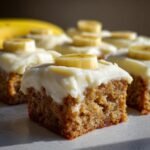 Close-up of irresistible banana bars topped with cream cheese frosting and fresh banana slices.