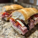 Close-up of an Irresistible Italian Sandwich filled with layers of cured meats, provolone cheese, roasted peppers, and a balsamic glaze.