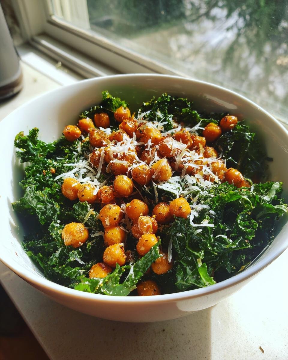 A bowl of Lemon Parmesan Kale Salad topped with crispy Hot Honey Chickpeas and shredded cheese.