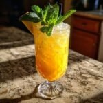A refreshing Missionary's Downfall cocktail in a glass, garnished with pineapple and mint, served over crushed ice.