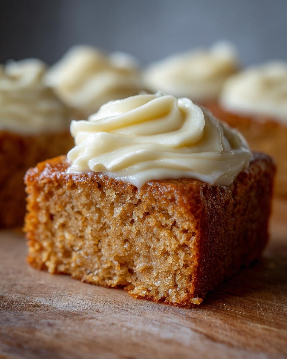 Close-up of irresistibly moist banana bars with swirls of cream cheese frosting.