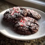 Three rich, dark chocolate Peppermint Hot Chocolate Cookies topped with powdered sugar and crushed candy canes.