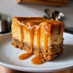 A decadent slice of Salted Caramel Pumpkin Cheesecake with thick caramel sauce dripping down the sides.