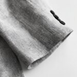 Detailed close-up of the texture of a grey seersucker blazer sleeve with black buttons.