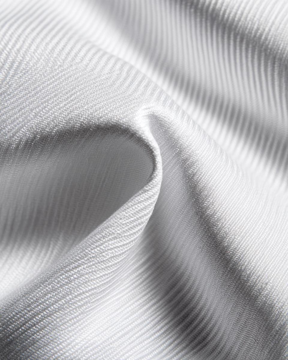 Detailed close-up of the puckered texture of white Seersucker fabric, showing its characteristic stripes.