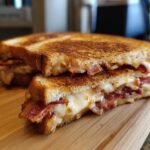 A close-up of a Southern Style Bacon Grilled Cheese Sandwich, cut in half to show melted cheese and crispy bacon.
