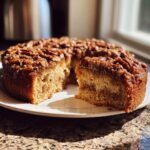 A slice of moist Sweet Potato Pecan Coffee Cake with a rich pecan topping on a white plate.