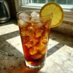 A tall glass filled with Traditional Southern Iced Sweet Tea, ice, and a lemon slice.