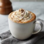 A close-up of the Ultimate Fall Spice Latte topped with whipped cream and a sprinkle of cinnamon.