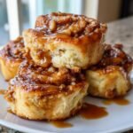 A stack of fluffy Vegan Apple Maple Cinnamon Rolls dripping with sticky maple glaze and chopped nuts.
