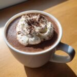 Close-up of a mug filled with rich Vegan Hot Chocolate With Coconut Cream, topped with whipped cream and chocolate shavings.