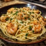 A close-up of a bowl of Weeknight Shrimp Alfredo Bucatini Pasta, topped with shrimp and parsley.