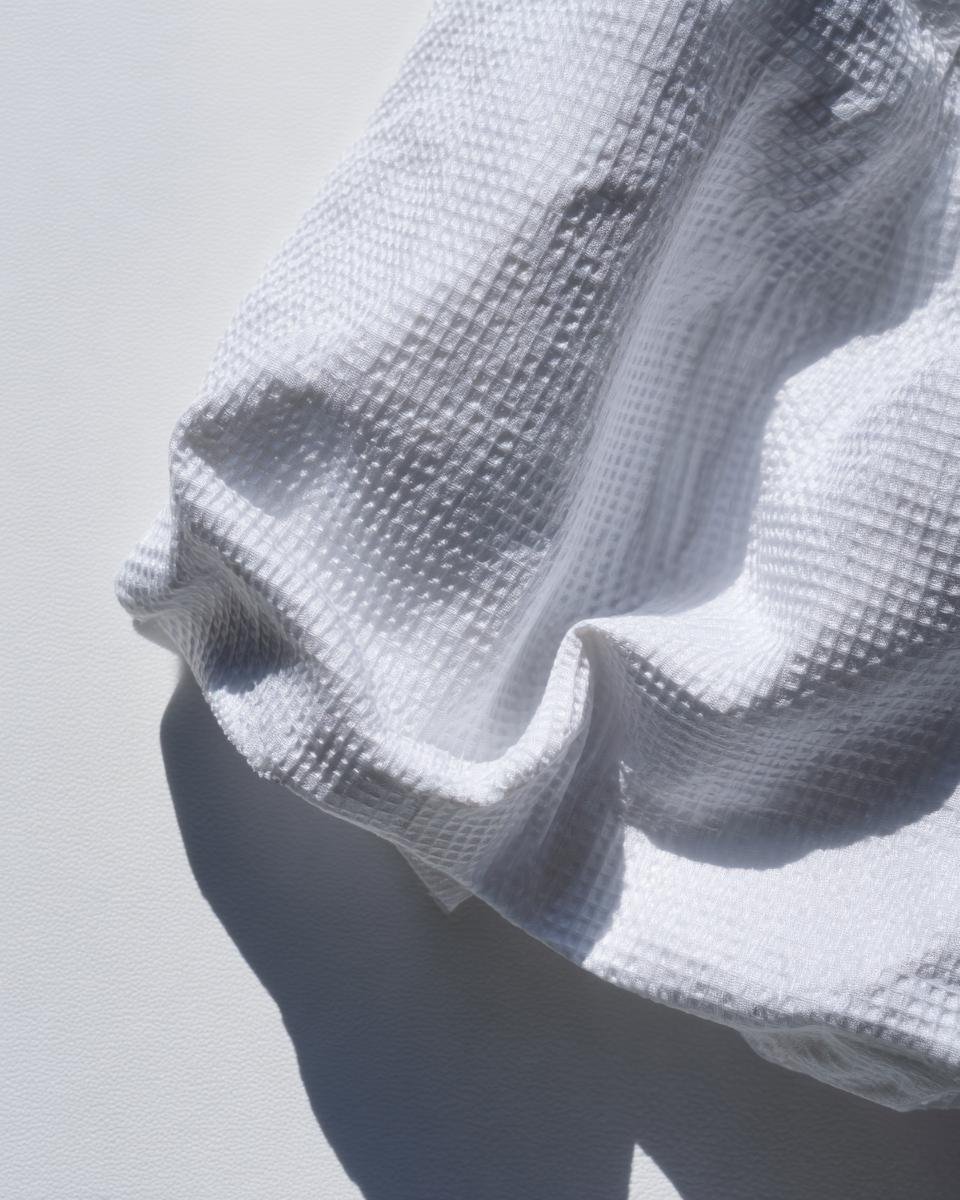 Detailed view of the puckered texture of white seersucker fabric, highlighting its characteristic weave.