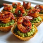 Close-up of several Cajun Shrimp Guacamole Tortilla Bites featuring seasoned shrimp on top of bright green guacamole in crisp shells.