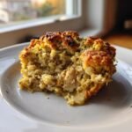 A close-up of a baked square serving of Chicken Stuffing Casserole on a white plate, showing moist interior and crispy top.