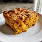 A close-up of a square slice of Cozy Pumpkin Baked Oatmeal on a white plate.