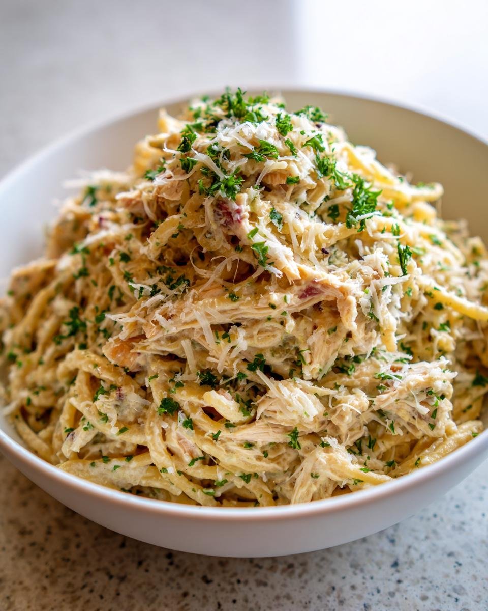 Close-up of a creamy Chicken Caesar Pasta Salad topped with shredded Parmesan and fresh parsley.