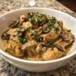 A white bowl filled with rich, creamy Instant Pot Chicken Marsala topped with sliced mushrooms and fresh parsley.