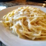 Close-up of fettuccine pasta coated in a rich, creamy Easy Garlic Parmesan Sauce, topped with grated cheese and pepper.