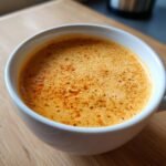 Close-up of a bowl of creamy roasted garlic cauliflower chickpea soup, topped with spices.