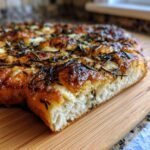 Close-up of a thick slice of Irresistible Crispy Flatbread With Brie Recipe, showing a fluffy interior and browned, herby top.