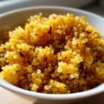 Close-up of fluffy, bright yellow Curried Fried Quinoa served in a white bowl.