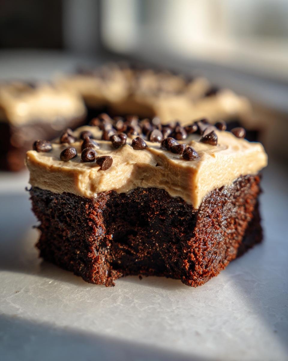 Close-up of a fudgy brownie square topped with Baileys buttercream frosting and mini chocolate chips.
