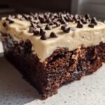Close-up of a rich, fudgy brownie slice topped with thick Baileys buttercream frosting and mini chocolate chips.
