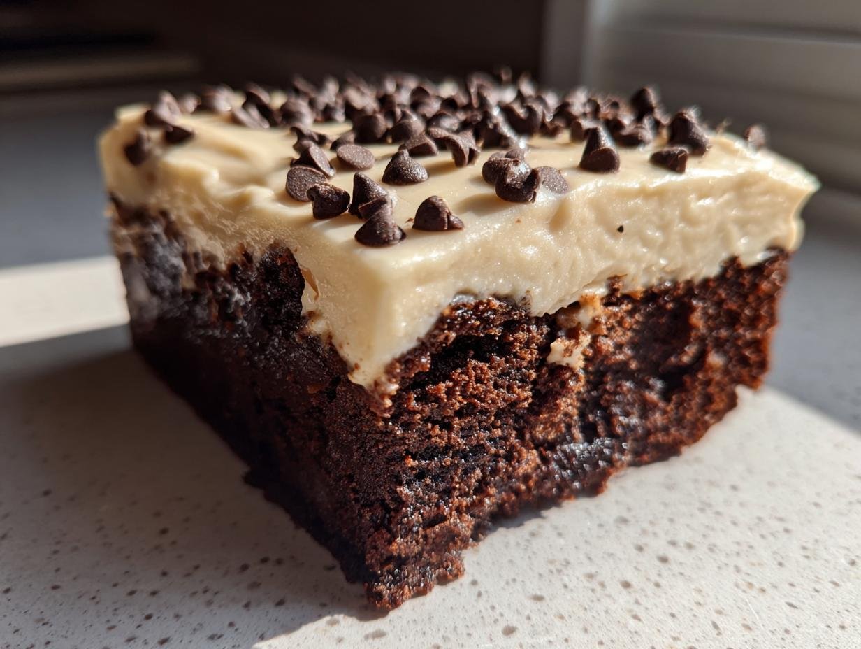 Close-up of a rich, fudgy brownie slice topped with thick Baileys buttercream frosting and mini chocolate chips.