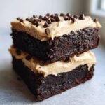 Two stacked, rich Fudge Brownies With Baileys Buttercream Frosting topped with mini chocolate chips.