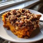 A close-up serving of Irresistible Golden Sweet Potato Casserole Recipe topped with crunchy pecans.