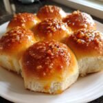 Close-up of freshly baked Hot Honey Garlic Dinner Rolls, glistening with a sticky glaze and topped with chopped nuts.